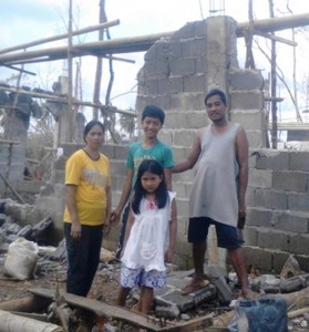 Fernanda family stand at ruins of home on Panay island, Nov 2012.