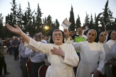 In this Saturday, Aug. 8, 2015 photo, Iraqi Christian refugees attend an outdoor prayer service to mark a year since their displacement, in Fuheis near Amman, Jordan. A year after tens of thousands of Iraqi Christians fled communities overtaken by Islamic State militants, their lives are on hold in exile: They won't go back to Iraq, saying it's not safe for Christians, but as refugees theyre barred from working in temporary asylum countries such as Jordan. Expectations of quick resettlement to the West have been dashed.  (AP Photo/Raad Adayleh)