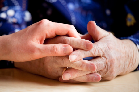 A young hand holding an elderly pair of hands